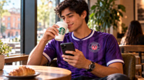 Un hombre mira su teléfono con una taza de café en la mano
